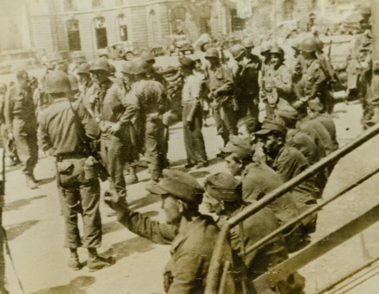 The Defeated, 8/6/1944. Rennes, France -- The liberation of Rennes, largest city to fall to the armies of liberation since the invasion of France, meant captivity for this handful of German prisoners. The beaten Nazis are shown outside Rennes City Hall. 8/6/44 (ACME);