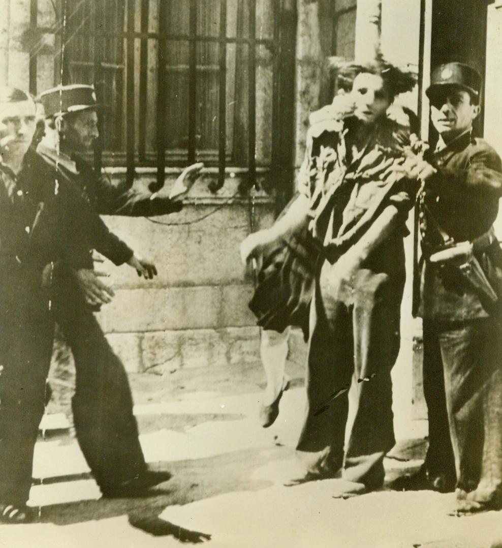 Aroused Avenger Gets Even, 8/22/1944. France -- An enraged woman (rear) tears at a captured Gestapo agent as Gendarmes attempt to placate her. The Gestapo man was responsible for the mutilation of her husband when the Nazis occupied the town of Brignoles, in Southern France. 8/22/44 (ACME);