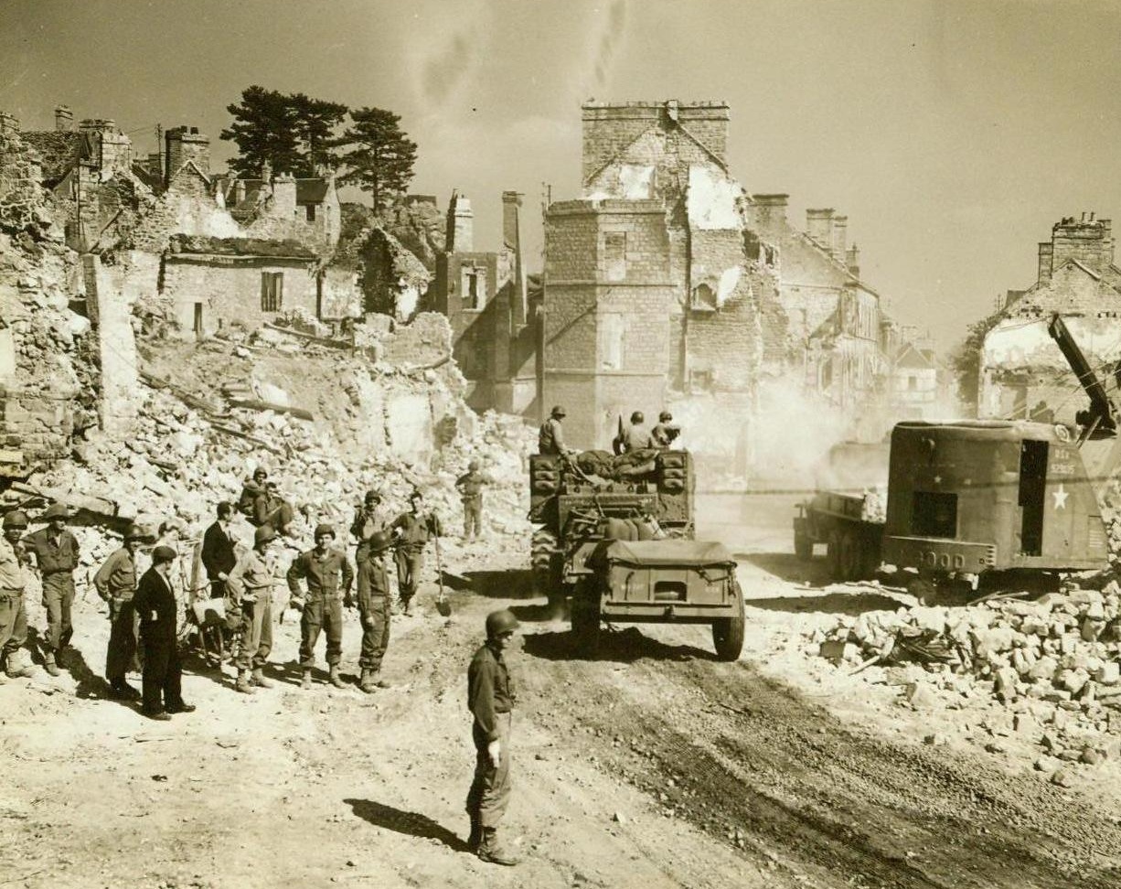 Erasing The Scars, 8/21/1944. France – As American troops race toward Paris, U.S. Army equipment begins to erase the battle scars from French towns along the way. Here a mechanical shovel clears great piles of rubble from this road in a battered town, permitting passage by heavier, front-bound vehicles 8/21/44 (ACME Photo By Bert Brandt, For The War Picture Pool);