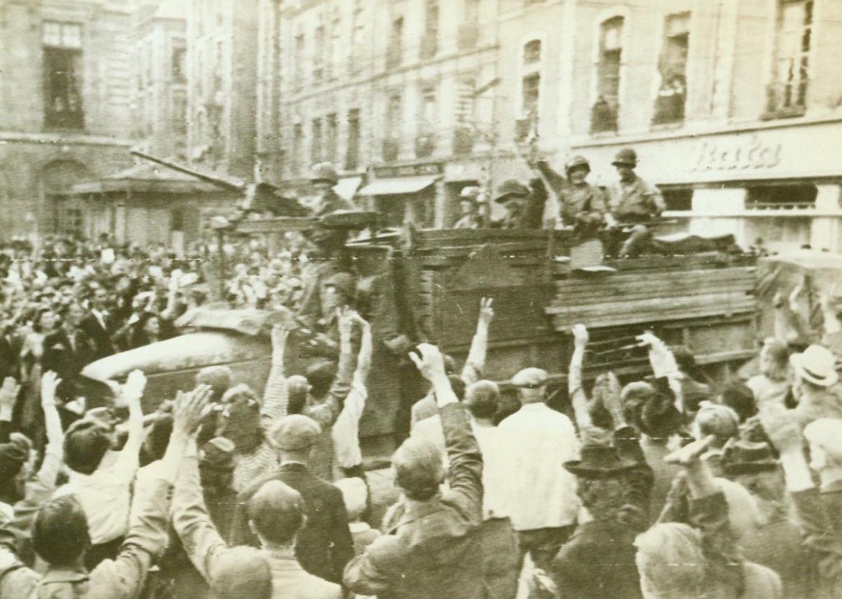 Hail The Heroes, 8/6/1944. Rennes, France – Wildly cheering, joyous natives of Rennes crowd around to welcome victorious Yanks into the liberated city. Waving and smiling from their armored vehicles, as the warriors return the greeting. 8/6/44 (Signal Corps Radiotelephoto from ACME);