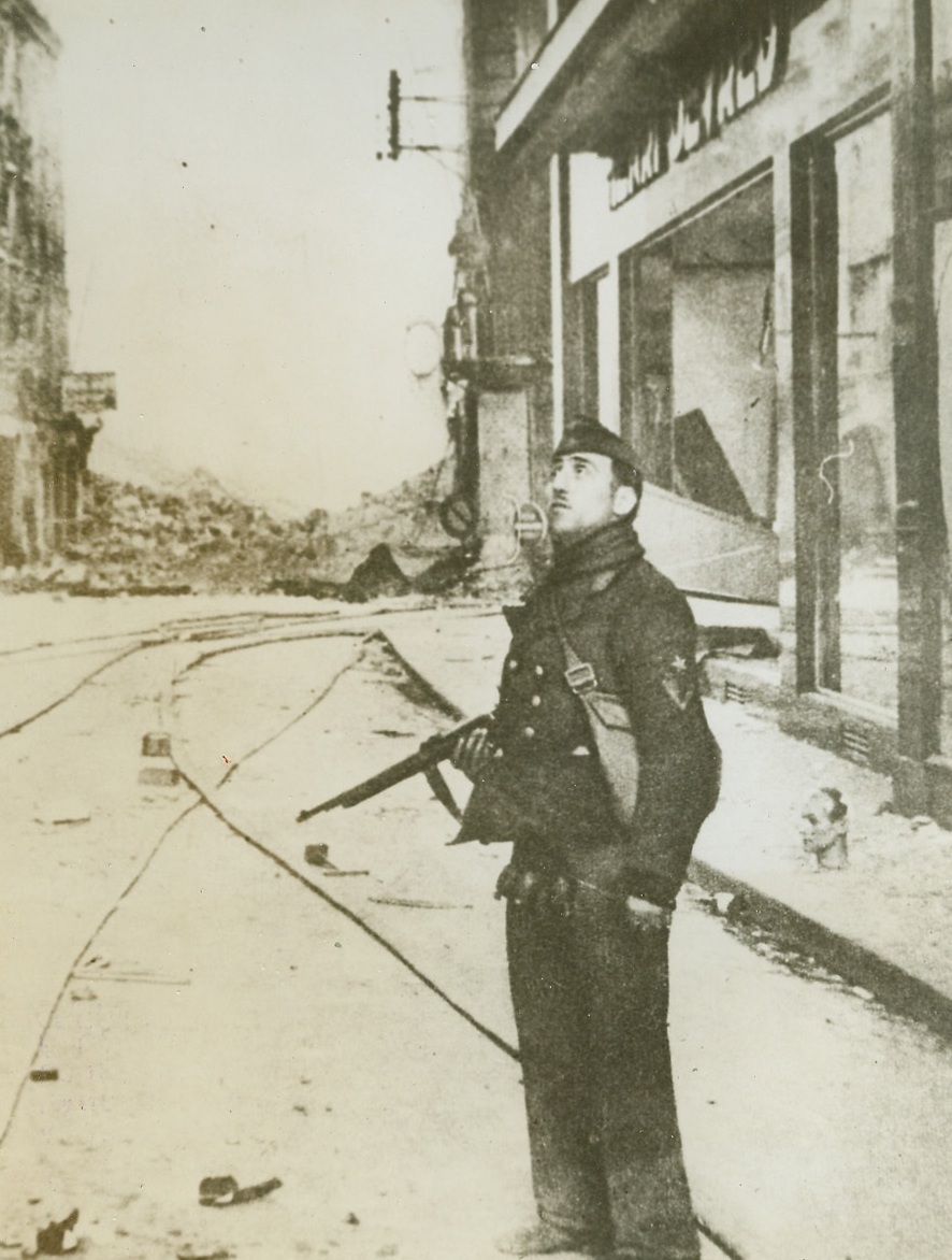 Caen During German Occupation, 8/1/1944. CAEN, FRANCE -- According to the German caption accompanying this photo received in London from a neutral source, this is a street in Caen after a British bombing attack which preceded its land onslaught on the city. A German soldier looks upward at the retreating planes. Credit (ACME);