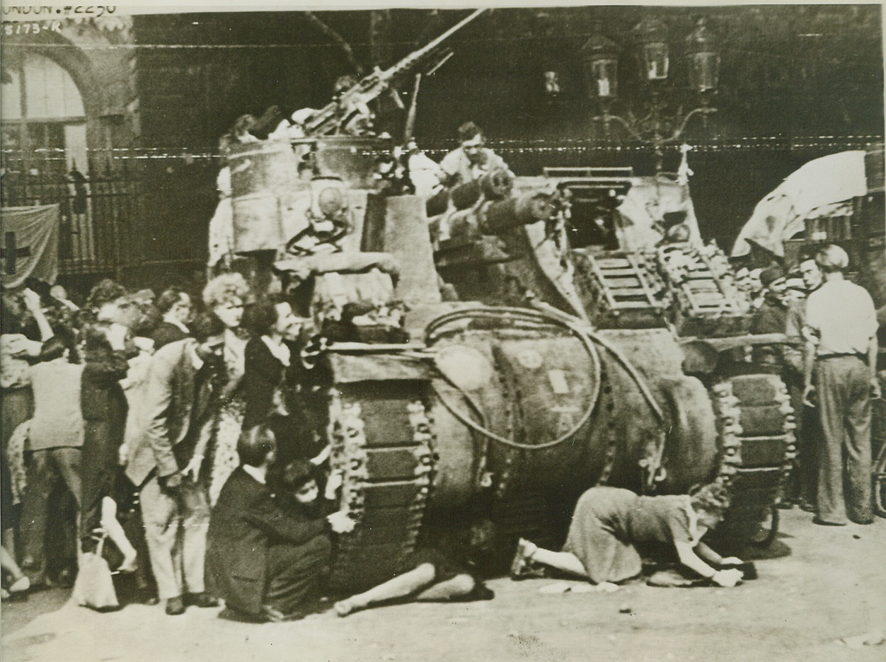 Seek Protection from Tank, 8/28/1944. PARIS -- Panic-stricken Parisians crouch close to a French armored tank for cover as snipers bullets whistle down from Notre Dame Cathedral. The terrified crowd was watching General De Gaulle enter the noted Cathedral for Thanksgiving services when the snipers attacked. British War Office Photo. Credit: (Army Radiotelephoto from ACME);