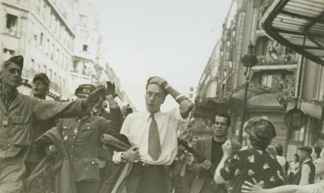 The Last Time They'll See Paris, 8/28/1944. FRANCE -- Captured Nazis are marched through Paris street under the careful and alert guard of the E.F.I. The man clasping his head is a German soldier who had dressed in civilian clothes and sniped at the French during the last days of the battle for the French capital. Credit (ACME Photo by Bert Brandt for the War Picture Pool);