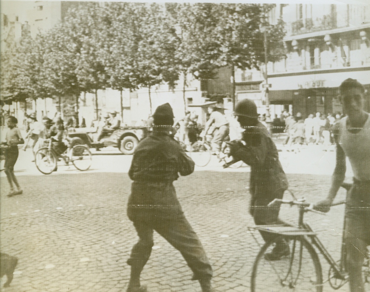 Paris Celebration Ends in Riot, 8/27/1944. Paris, France—A few minutes before the scene of a triumphal procession celebrating the liberation of Paris, this street in the vicinity of the Eiffel Tower is now filled with people scrambling to escape the rifle fire of Nazis and collaborationists quartered in nearby buildings. It was during this procession that an attempt was made on the life of Gen. de Gaulle. The photographers in the foreground, taking pictures as the people scramble for shelter, are probably war picture pool correspondents.  Credit: ACME photo via Signal Corps;