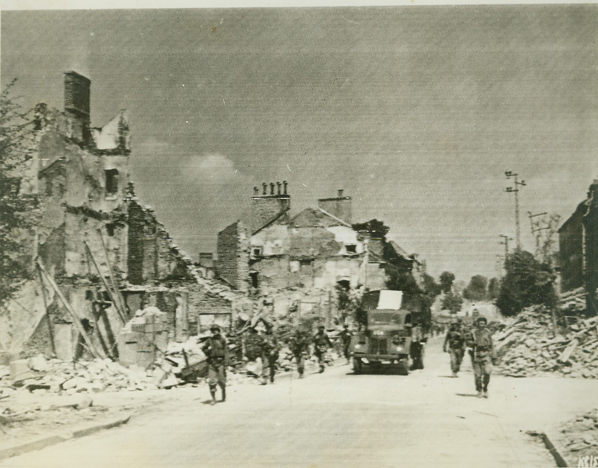 In Pursuit of Germans, 8/8/1944. France—American Infantrymen move through Mayenne on the heels of German forces, fleeing in the face of the American blitz offensive. Buildings were blasted by U.S. bombers. Credit: Army radiotelephoto from ACME;