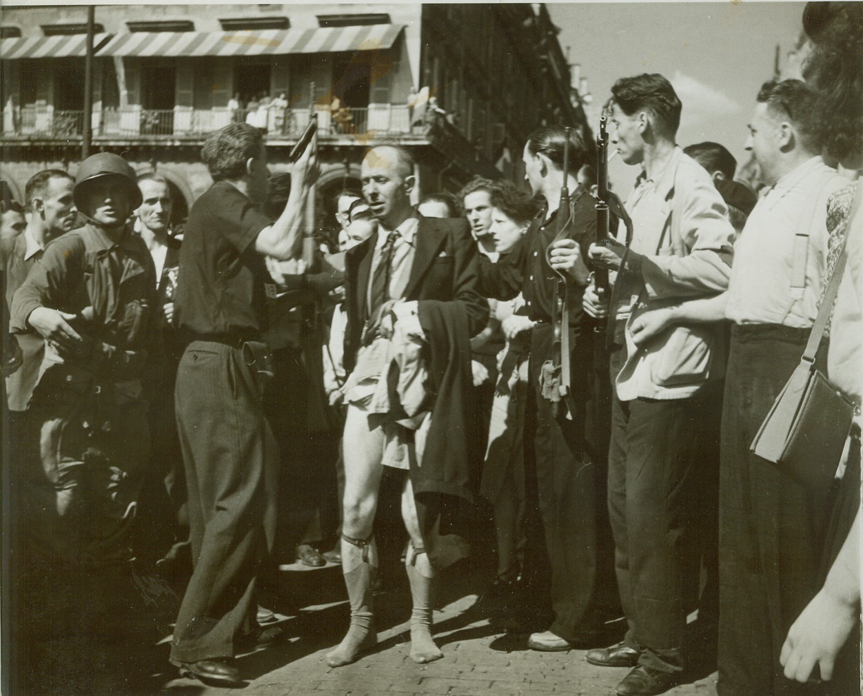 Collaborationist Who Needed “Protective Custody”, 8/28/1944. Paris—This collaborationist who lost his pants to an angry group of Parisians is shown being saved by the F.F.I. and taken into their protective custody. Credit: ACME photo by Bert Brandt for the war picture pool;