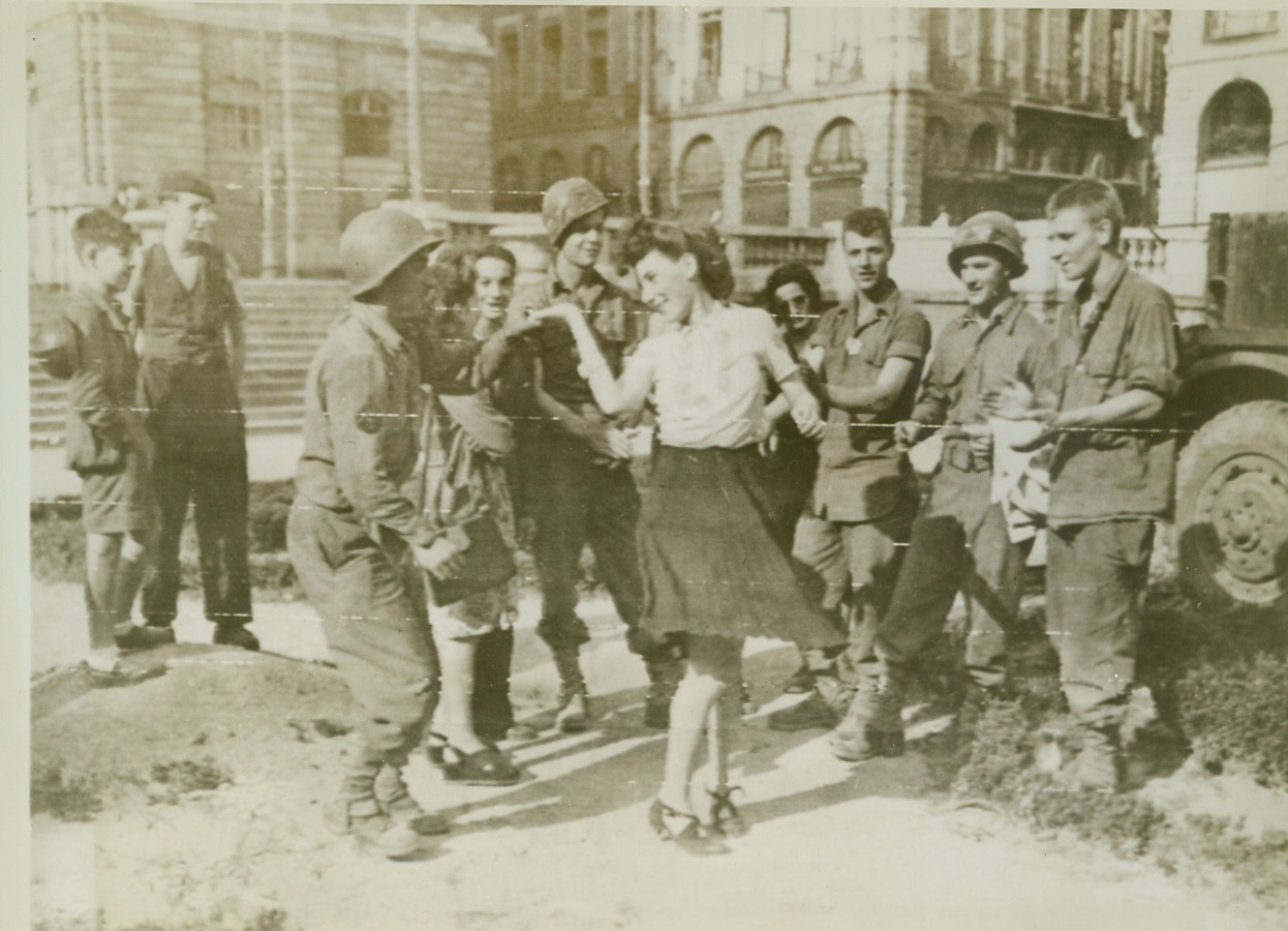 G. I. Jitterbugging, 8/6/1944. Rennes, France—So great was their joy over the Allied capture of Rennes that natives of that great city literally danced in the streets. Here a pretty French girl cuts a rug with Rosario Talliento, a G. I. from Brooklyn, New York. Credit: Signal Corps radiotelephoto from ACME;