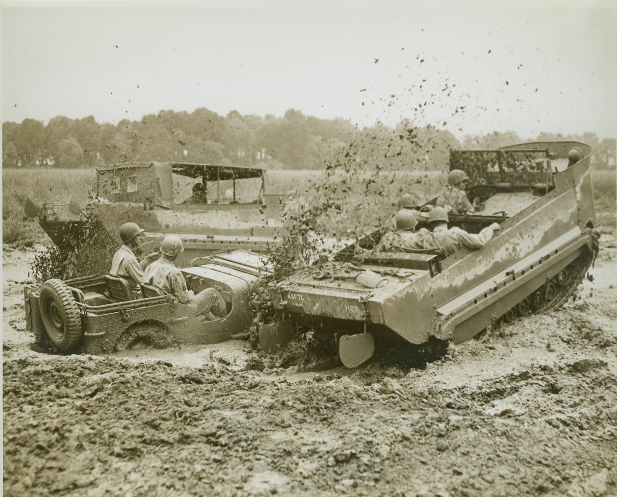 THE M-29, ALL PURPOSE CARGO CARRIER, 9/1/1944. ABERDEEN, MD. – The “Weasel”, M-29 Light Cargo Carrier, sloughs through the mud as it bypasses a stranded jeep on the proving grounds at Aberdeen, MD. The M-29, which is used on amphibious and swamp operations, has a full tack and rudders, and is capable of amazingly high speeds on the ground. Credit: OWI Radiophoto from ACME;