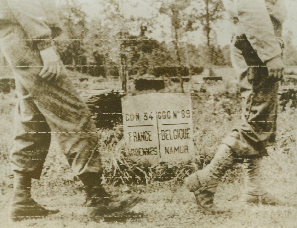 Over the Border, 9/3/1944. The feet of American soldiers tramp across the French-Belgian border, passing a tiny boundary marker. American units have now advanced forty miles inside Belgium. Credit: SIGNAL CORPS RADIOTELEPHOTO FROM ACME.;