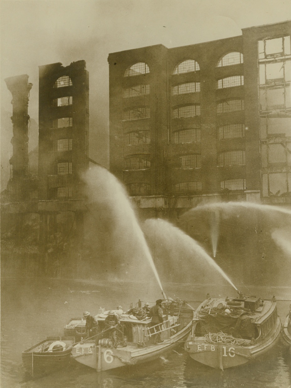 Fire in London Dockland Area, 9/20/1940  LONDON -- Working from emergency fire boats, firemen send streams of water into a burning building, fired by the Nazi air raids on the dockland area of London.  Credit: (ACME);