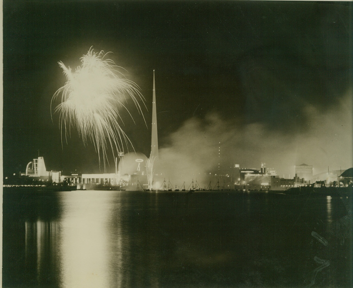 BOMBING SCENE – AMERICAN TYPE, 10/9/1940  NEW YORK CITY – Like a picture from the war zone is this scene of bombs bursting in air with blazing buildings forming the backdrop. The scene, however, is one of beauty and not one of horror. It is a view across Liberty Lake at the New York World’s Fair during the fireworks display on a cool, clear autumn night. Credit: ACME photo by staff cameraman Carl Thusgaard;
