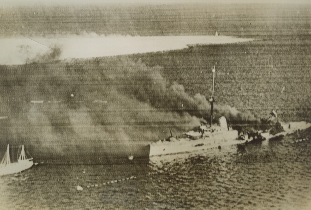 Italian Warship Burning at Fall of Tobruk, 2/7/41  TOBRUK—The Italian cruiser San Giorgio ablaze in Tobruk Harbor as the Italian stronghold fell to the combined British land, sea and aerial forces. Photo cabled from London to New York. Credit: ACME CABLEPHOTO.;