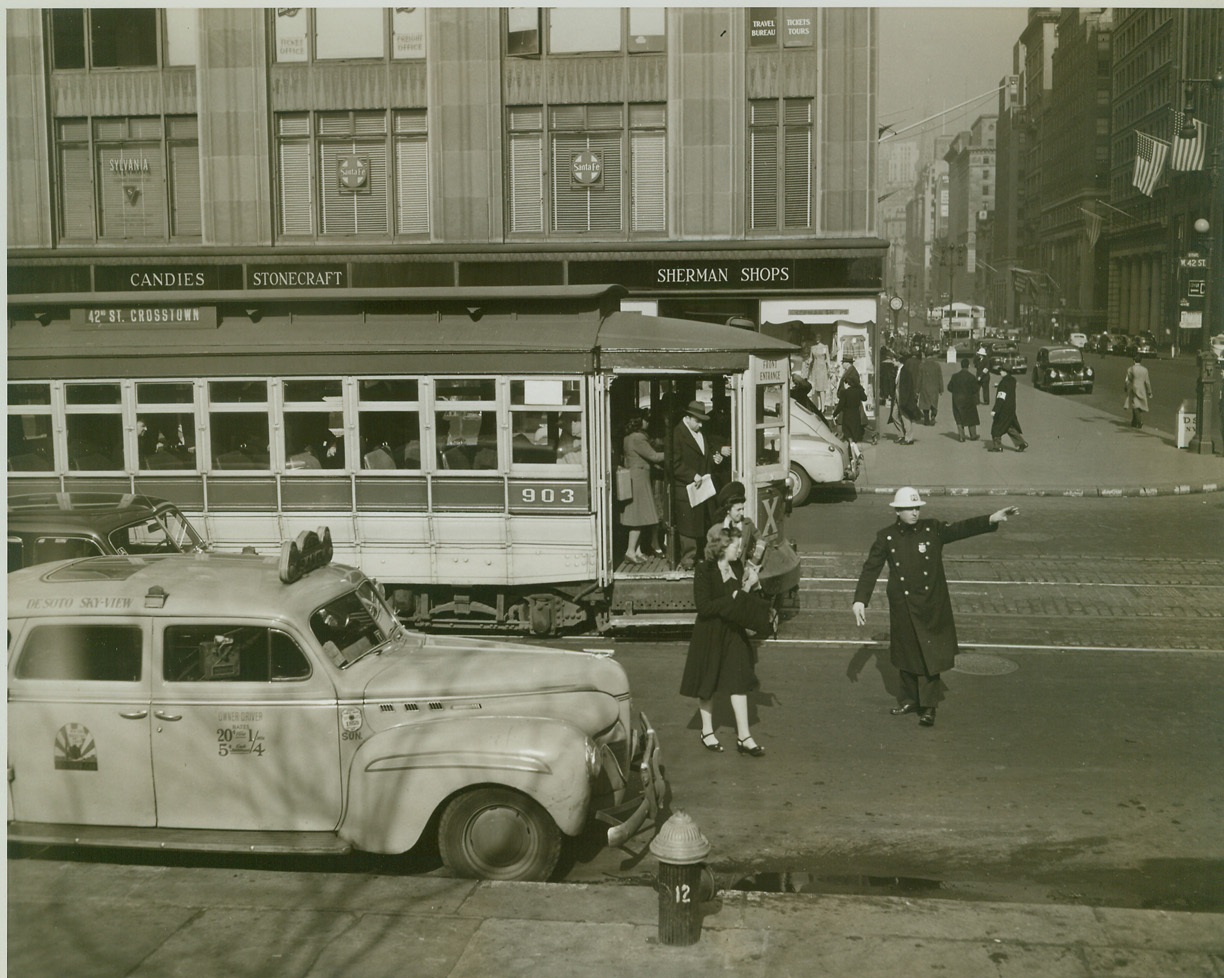 SEEK SHELTER!, 2/20/1943. NEW YORK CITY – Stopping a trolley car at 42nd Street and Fifth Ave., a policeman orders passengers to leave the car and seek shelter in nearby buildings as the “red” signal sounds. Photo was made during the third successive air raid alert under the new signal system in New York City today (February 20). Credit: OWI Radiophoto from ACME;