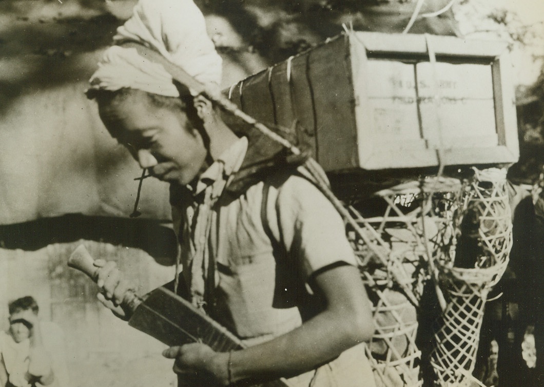 NAGAS DO PORTER DUTY IN INDIA, 2/19/1943. SOMEWHERE IN INDIA—A typical Naga, the type of Indian native who is carries supplies for U.S. troops in India, all set and ready for the hike. The pack harness has a wooden yoke for his shoulders and the basket contains rice and other coolie rations. On top of the basket is a case of U.S. Army field rations “C” which weighs about 40 pounds. The little Nagas usually carry 60-pound loads. Credit: Official U.S. Army photo from Acme;