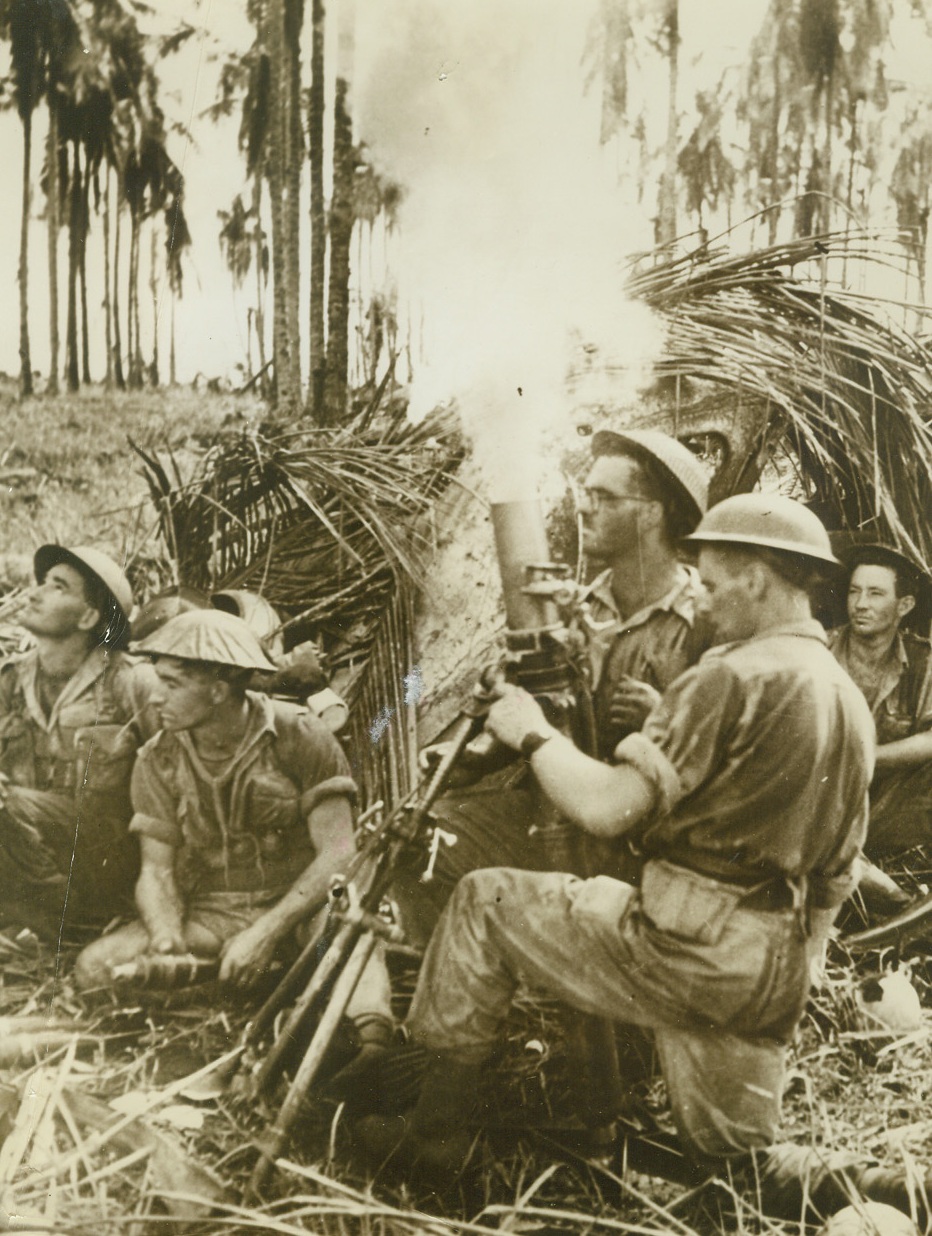 Nipping the Japs, 2/8/1943. New Guinea – An Australian mortar crew lays down a barrage at the Japs near Buna.  Note that the guns are almost pointing straight up – showing the nearness of the enemy.  This is one of the first pictures showing the final assault on the port of Buna in New Guinea.Credit Line (ACME);