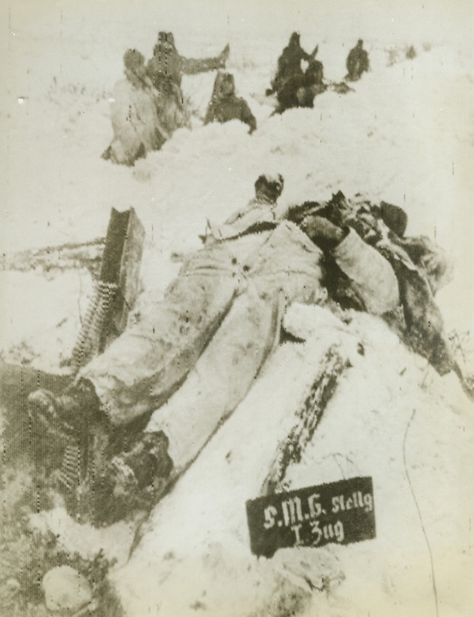 SILENCED FOREVER, 2/5/1943. ON THE RUSSIAN FRONT—This enemy machine gun will never again spit bullets at Red Army men. The Nazi gunner lies on a mound of snow as Red Army machine gunners fire at retreating Germans in the background. Latest reports from the Soviet front indicate that Russian troops, smashing westward in the Caucasus, have split German forces, pinning one body against the sea and pressing another back toward  Rostov. Credit: ACME RADIOPHOTO.;