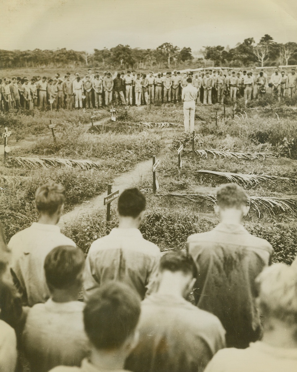 Pay Homage to Departed Comrades, 2/2/1943. Guadalcanal: - With heads bowed, American soldiers stationed on Guadalcanal, in the Solomon islands, pay their last respects to buddies who were victims of the Japs.  A cross and palm leaf mark the resting places of the fallen men. Credit line (ACME);