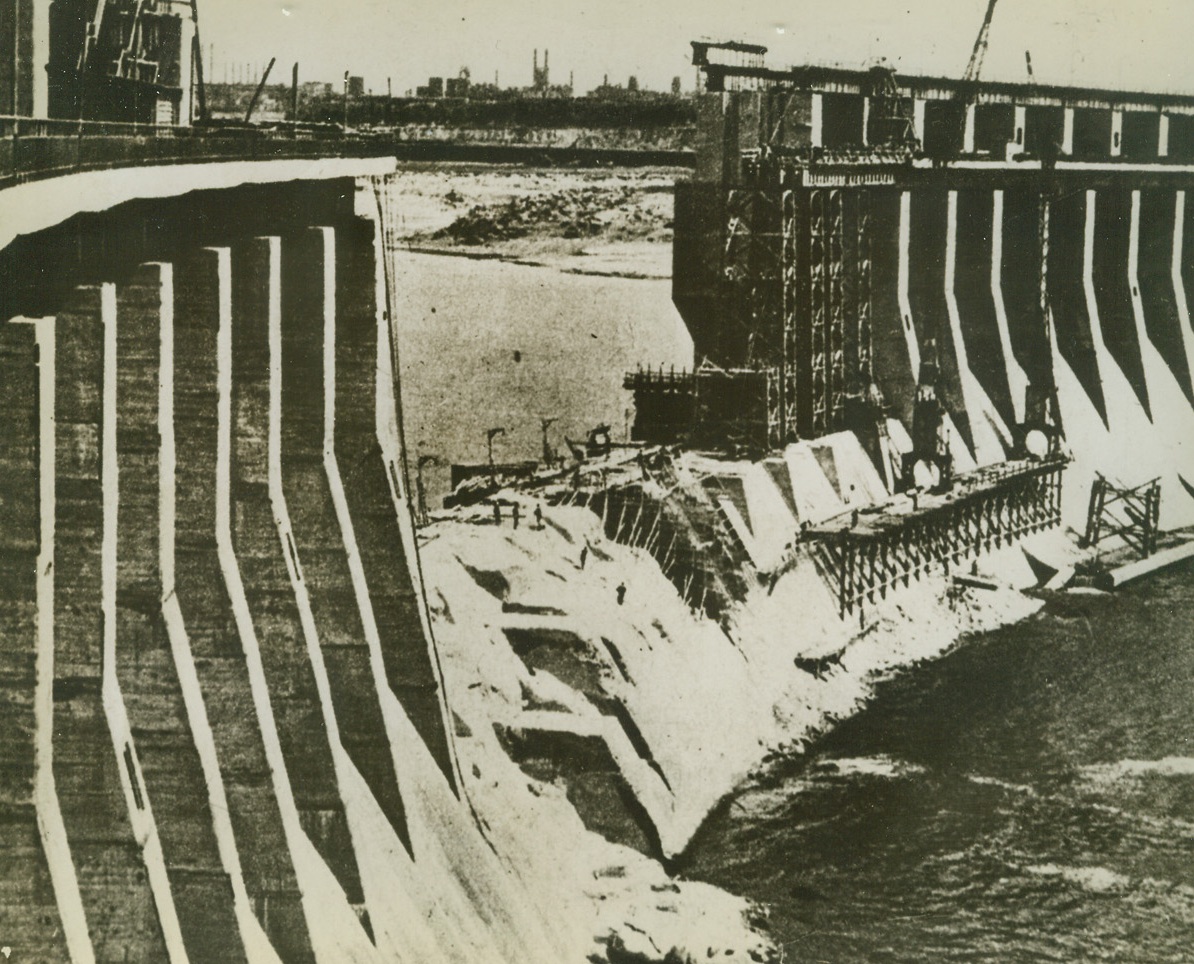 Nazis Repairing Dnieprostroi Dam, 2/13/1943. Russia—Here is a section of the Dnieprostroi Dam, which was blown up by the Russians when they left that area in August 1941 and which is now being repaired by the Nazis because the entire Central Ukraine Industrial District depends on this world’s greatest hydro-electric power works. If the present Russian advance continues at its fast pace, this Nazi repair work may come in handy as the Red Army moves southwest from Kharkov. The Germans may not have time to blow the dam up again. Credit: ACME.;