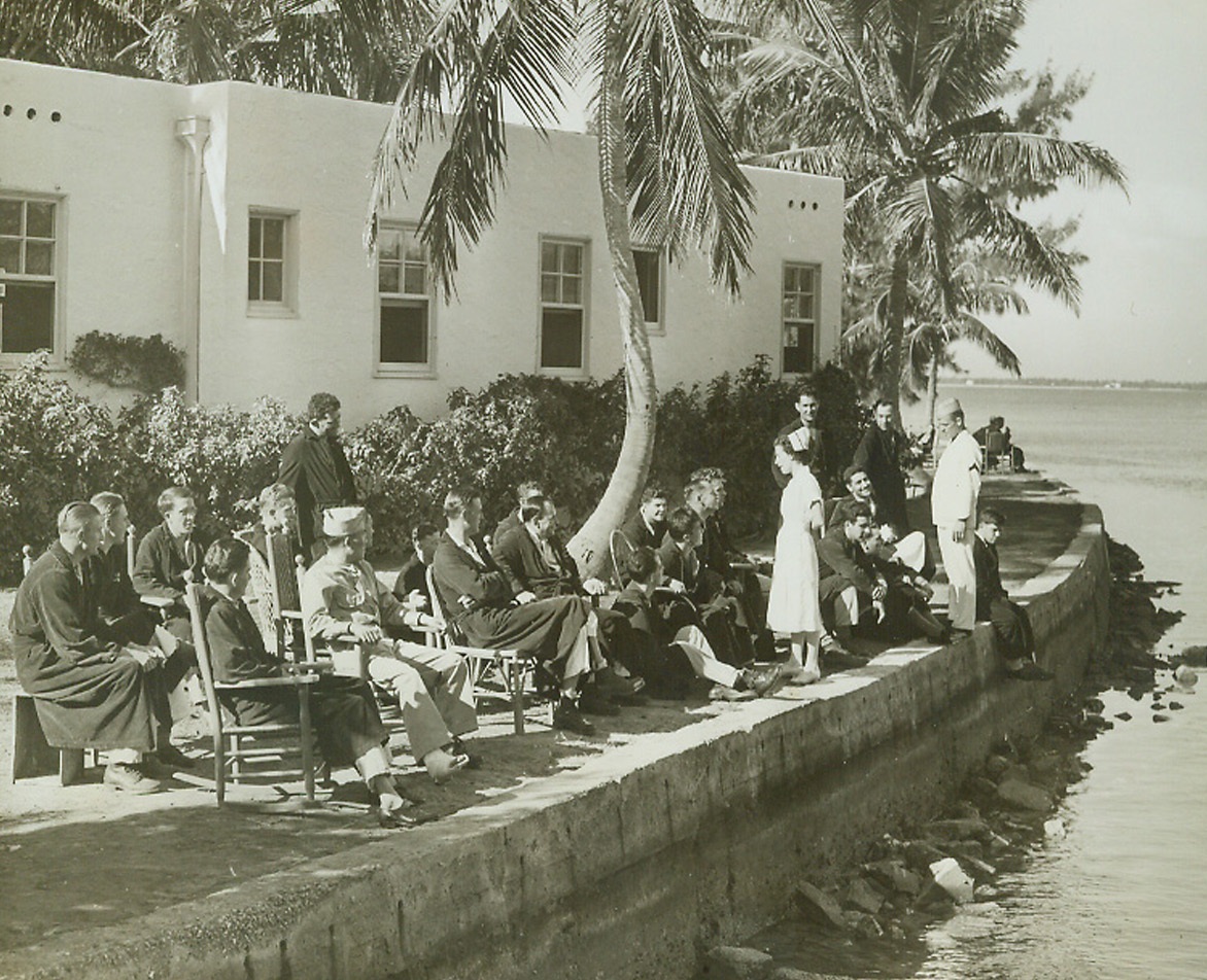 Convalescent Soldiers, 2/5/1943. Miami Beach, Fla.—Convalescent soldiers get a bit of that famous Florida sunshine as they sit along the waterfront outside the Nautilus Hotel Cottage Center. They are men who are stationed with the Army Air Forces at Miami Beach. The Nautilus Hotel has been taken over by the Army to serve as a hospital for the training center at the famous resort. Passed by censors.Credit: ACME.;