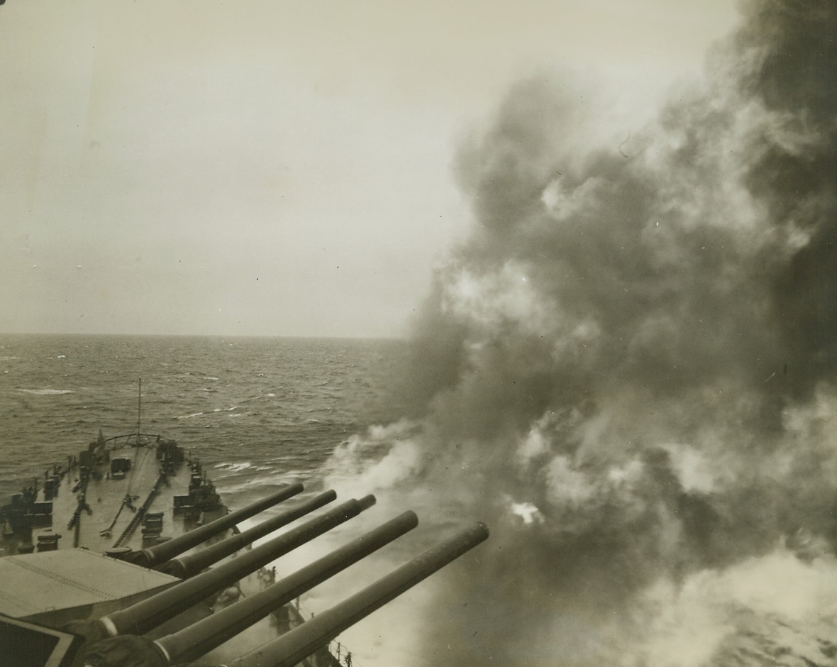 Sixteen Inch Salvo, 2/3/1943. The main battery of 16-inch guns blast away over the starboard side of a U.S. battleship on a cruise and target practice sea jaunt. There’s no enemy this time to feel the deadly combination of American skill and might. Credit: ACME;