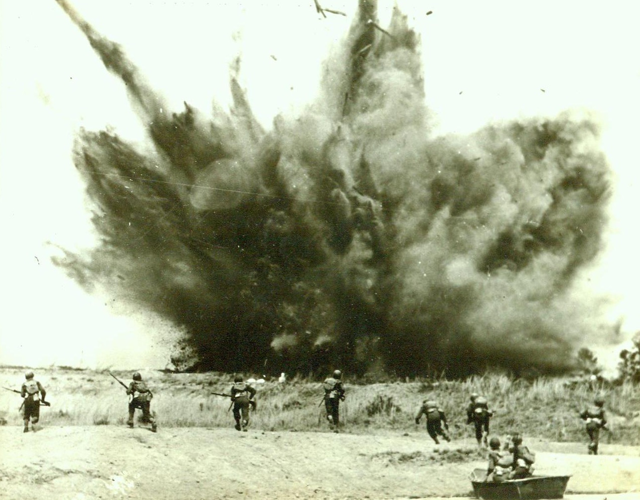 Wildcat Division Tastes Real War, 2/8/1943. Camp Rucker, Ala. -- Advancing under a barrage of live ammunition, units of the 81st (Wildcat) division were treated to a taste of actual warfare as they advanced across Lake Tholocco at Camp Rucker, Ala., in assault boats and stormed a "Nazi" village on the opposite shore. The exercise, planned to develop teamwork between all ground forces, saw nearly a thousand men in action as field artillery and infantry weapons threw live fire overhead.  Photo shows a pillbox being blasted as infantrymen make a beach landing from their boats. 2/8/43 (ACME);