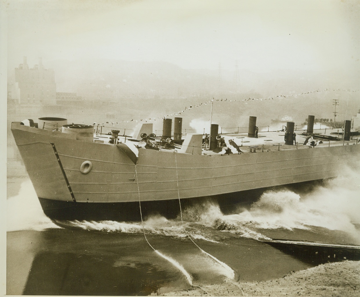 New Type Offensive Craft Launched Inland, 2/1/1943. AMBRIDGE, PA. – A new type tank landing ship splashes into the Ohio river after skidding down the ways of the Navy shipyard built and operated by the American Bridge Company. The U.S. steel subsidiary launched the new style vessel today, exactly nine months from the date workmen began converting 64 swampy acres into an inland shipbuilding plant. The conversion work involved changing the course of a creek, constructing a highway and bridges and erecting 23 buildings. Credit: (ACME);