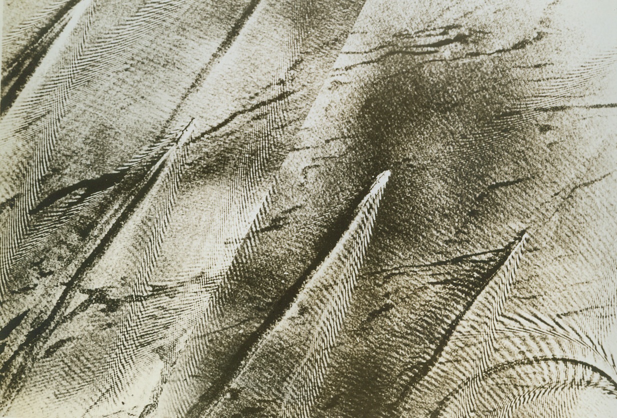 Sea of Patterns, 3/1/1943. This strange Herringbone pattern is etched by ships of an enemy convoy off the Island of Pxis in the Ionian Sea. Anticipating an air attack, which presumably followed, they began to disperse at full speed ahead to make the target more difficult. Notice at upper left, one vessel has started to spin a circle in an evasive tactic. The three center ships are merchantmen laden with deck cargo. Credit: BRITISH INFORMATION SERVICE FROM ACME.;