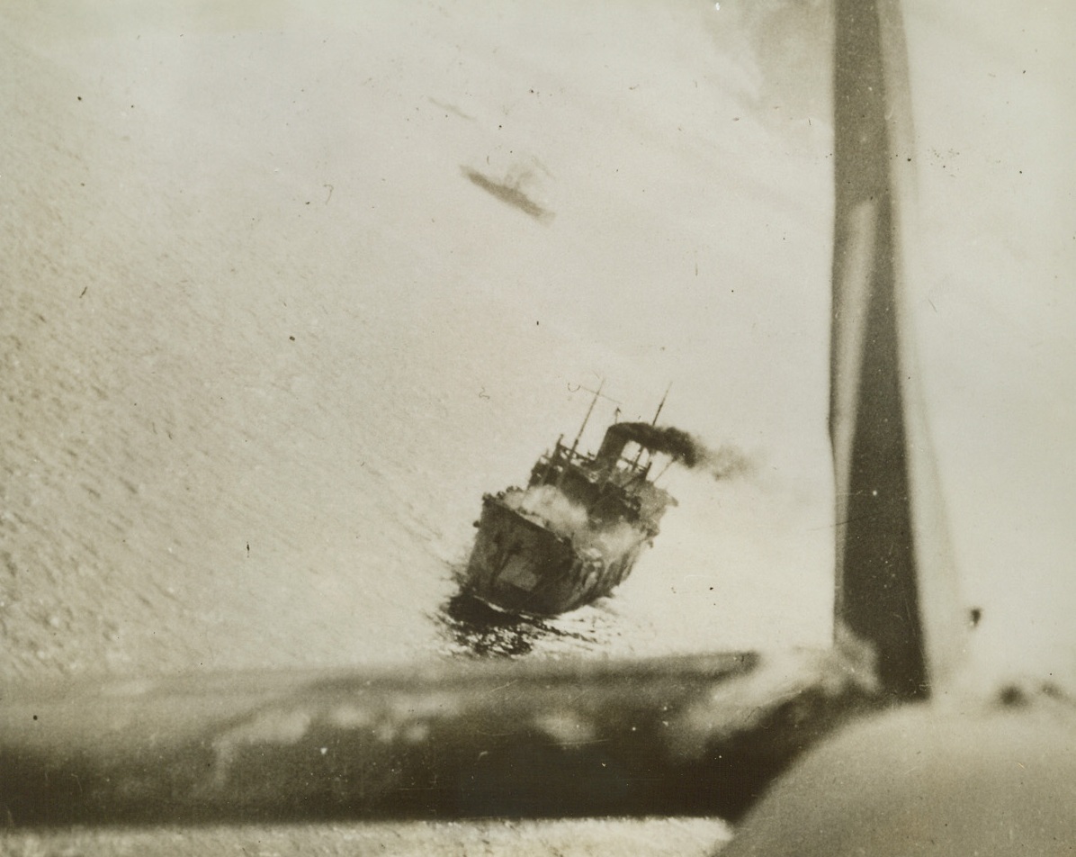 You’re Looking at a Strafed Jap Ship, 3/20/1943. “Somewhere in the Bismarck Sea” in the South Pacific war zone, this photo was made of a 10,000-ton Jap transport vessel that had just been strafed during the recent naval-air battle in which a 22-ship enemy convoy was wiped out. The tail of the long-range fighter plane which did the strafing is shown in the picture. Other ships in the Jap convoy can be seen in the distance. Credit: Official Royal Australian Air Force photo from ACME;