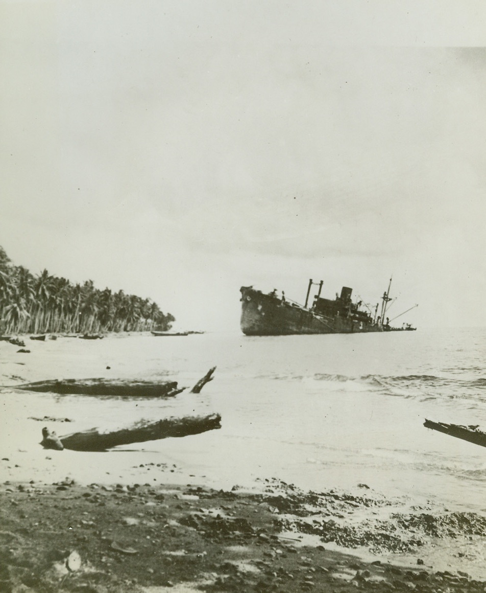 BLASTED AND BEACHED,3/7/1943. GUADALCANAL, S.I.—Blasted by American forces in the Solomon Island battles of November 13 and 14, 1942, the Jap ship, Kinugawa Maru, lies useless and deserted off Guadalcanal. Half of the beached vessel is almost submerged beneath the waters of the Pacific. Credit: ACME.;