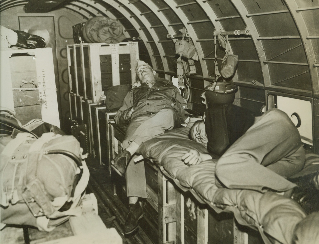OXYGEN RATIONED OVER HIMALAYAS, 3/9/1943. EASTERN INDIA—Only the all-important crew is entitled to oxygen, so a U.S. Army major and colonel sleep as best they can atop rifle cases in a transport plane speeding over the Himalayas toward China at an altitude of 18,000 feet. “Deadheaders,” as passengers are called, shift for themselves when aboard a flying freight car that links India and China by airways that cut through rarified atmosphere.  Credit: ACME;