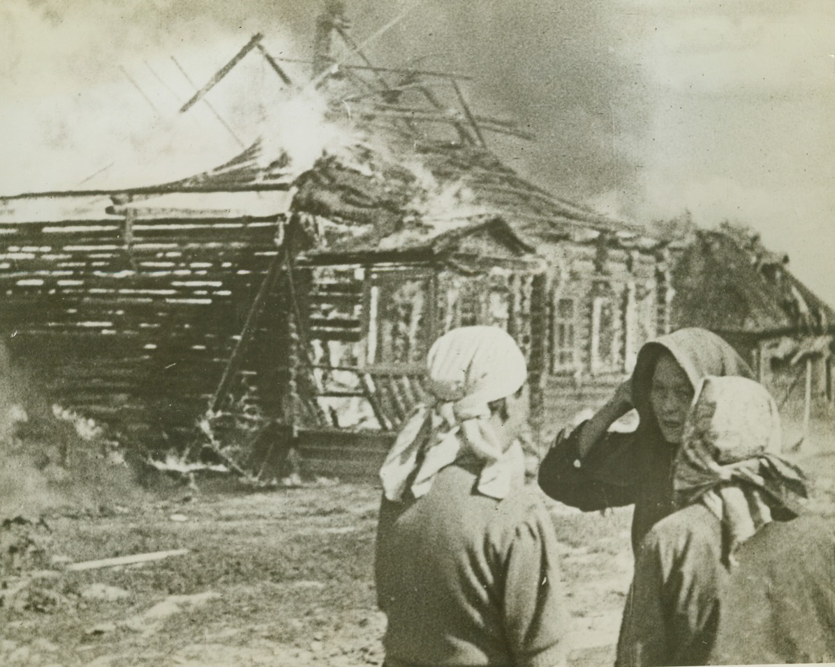 Their Homes Go Up in Flame, 3/5/1943. Flash from “one day of war”.  This photo is from the march of time’s “One Day of War”, a documentary film of one day on the far-flung Russian front, recorded by soldier-photographers of the Red Army.  Of the 160 photographers assigned to the job, thirty were dead before the day ended. Photo shows” Women stand helplessly by, and watch their homes go up in flame as Nazi troops flee their village in the face of a Red Army Advance.  Spiteful Nazis put the torch to everything that would burn, leaving a flaming village to greet the attacking Reds. Credit line (March of Time’s “One Day of War” photo from ACME);