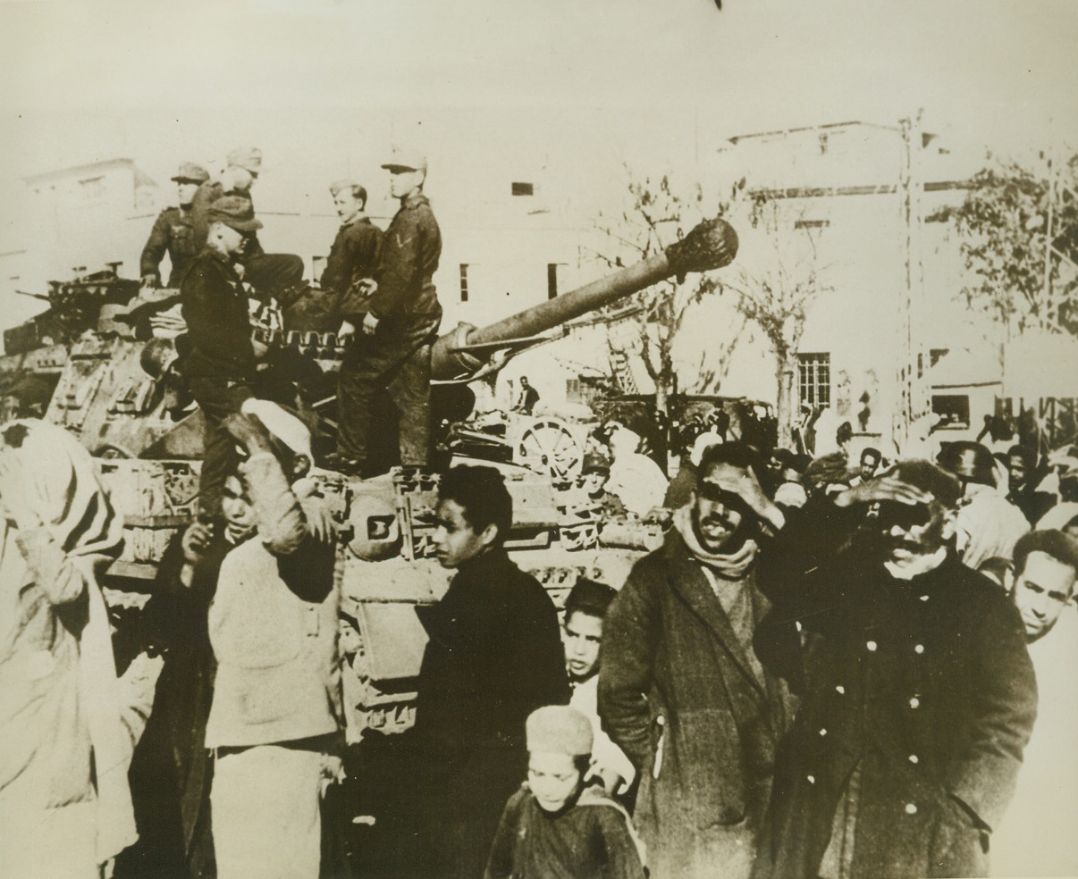 German Tank Forces in Tunis, 3/1/1943. According to the caption on this German photo, which has just arrived in New York by way of Lisbon, Nazi tanks are shown rolling through Tunis.  The caption, however, neglected to explain why the natives in the picture --- as well as members of the  one tank crew – are looking at something other than the tanks. Credit line (ACME);