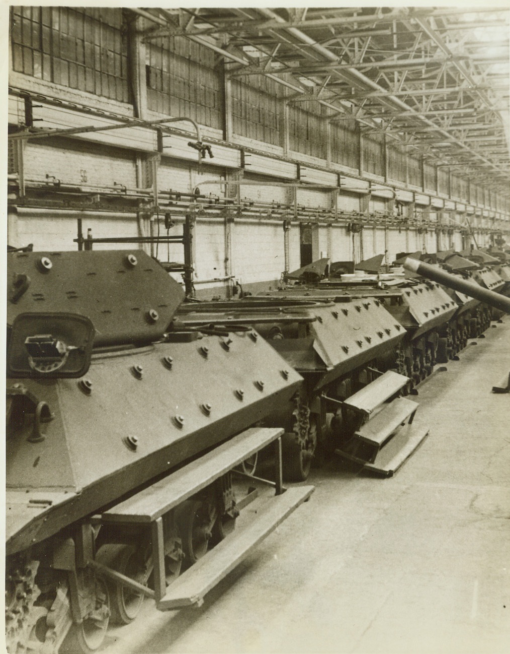 New Tank Busters on Production Line, 3/11/1943. DETROIT, MICH. – A long line of new M-10 tank destroyers minus their treads, on the production line at a Detroit plant of the Ford Motor Co. These hard-hitting tank busters have been rolling out of the plant for several months and have seen action in North Africa, where they are pronounced a success by the Allies. The M-10 in left foreground has already had its turret put in place. Next one in line waits for its turret, the gun of which can be seen at right, (center of photo). Credit: (ACME);