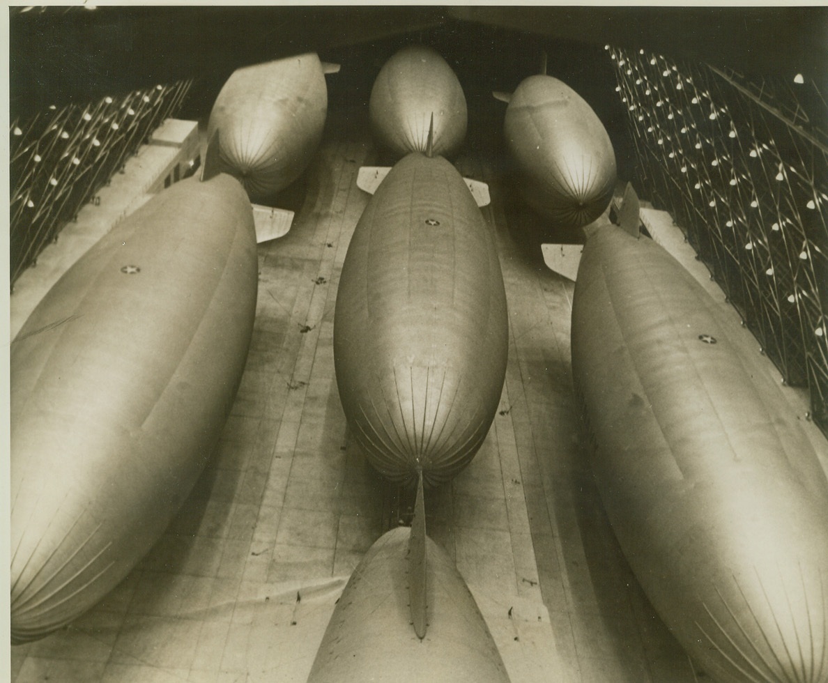 Sea Lane Protectors, 3/3/1943. Taken inside one of the U.S. Navy’s great airship hangars, on “docks,” photo shows parts of seven off-duty blimps. The non-rigid patrol ships are a vital component of the naval forces that protect important sea lanes off American shores, part of the Navy’s anti-submarine arm. Credit: Official U.S. Navy photo from (illegible portion of caption);