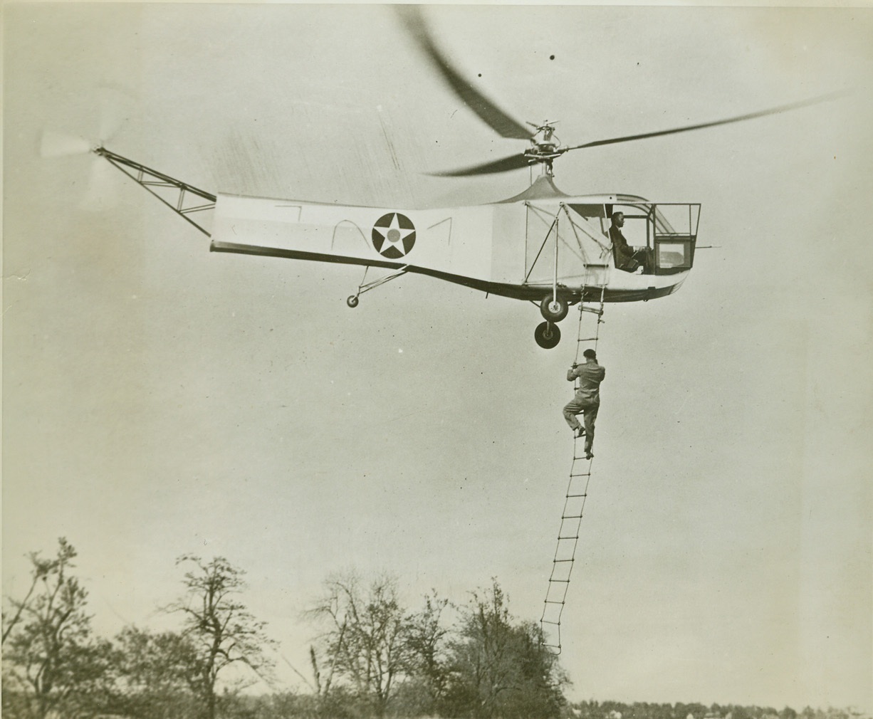 Hey—Wait For Me!, 3/6/1943. Washington, D.C.—Getting aboard the Sikorsky helicopter is an easy matter for the tardy passenger who missed the takeoff. The pilot merely drops a ladder and allows the plane to hover motionless. 30 feet above the ground, as his passenger climbs the rope ladder. Because of its many military uses, the two-place helicopter has been developed for the U.S. Army. Among its more important features is the facility with which the helicopter lands and takes off in limited space. Credit: ACME;