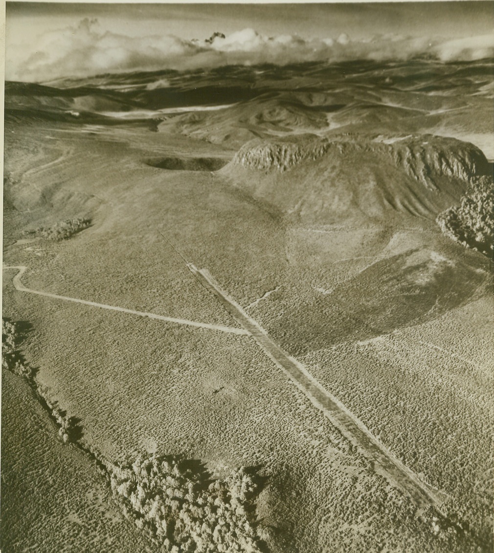 RIBBONS OF ROAD, 3/10/1943. MOUNT KENYA – Weaving across the rugged moorland on the slope of Mount Kenya like narrow strips of ribbon, this road and runway were built so that an RAF plane, forced down on the mountain, could return to its home base. Gathering rocks and stones to fill holes, and cutting heather and brush, 150 natives built the runway after four solid weeks of work. A road (at left) was cut from the marooned aircraft to the runway at the same time. Credit: OWI Radiophoto from ACME;
