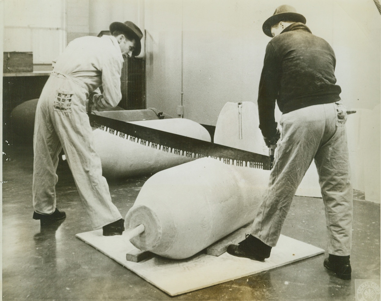 WE WOULDN’T WANT THIS JOB—WOULD YOU?, 3/12/1943. RAVENNA, OHIO—It isn’t as dangerous as it seems! These men two workers at the 30,000 acre governmental Ordnance plant here are sawing through the core of a one-ton bomb, said core being amatol, a high explosive that blow the steel of a bomb asunder and writes finis to Axis designs on world domination. Cores are subjected to this test during munitions making to determine solidity. Credit: OWI Radiophoto from ACME;