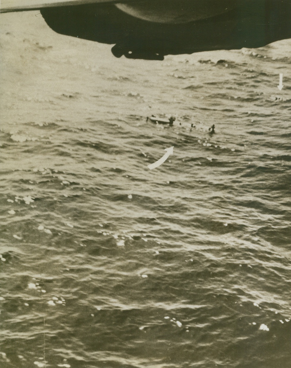 “Tidewater Tillie” Scores Again, 5/25/1943. The crew of a specially equipped Liberator B-24 bomber of the U.S. Army Air Forces anti-submarine command made this photo of a successful attack on a Nazi U-boat, proving they had scored a “kill”. Once before they had attacked an enemy sub and had been given credit for only a “probable”, because their photos hadn’t shown conclusively that the undersea boat was destroyed. This time, photos of the attack, and of the wreckage on the surface after the attack, made the “kill” a certainty. Here, after depth bombs from the plane had blasted the sub to the bottom, survivors of the crew cling to a cylindrical object, (left arrow), and others float in the water, (arrow far right):  Credit Line (U.S. Army Air Forces Photo From ACME);