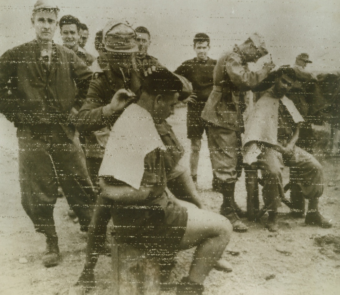 GETTING “THE WORKS”, 5/26/1943. Italian prisoners, captured during the latter part of the Tunisian campaign, get “the works” at the desert barber shop set up within the barbed wire barriers of their prisoner-of-war camp. Why the primping, boys, you aren’t’ going anywhere? Credit Line (OWI Radiophoto from ACME);