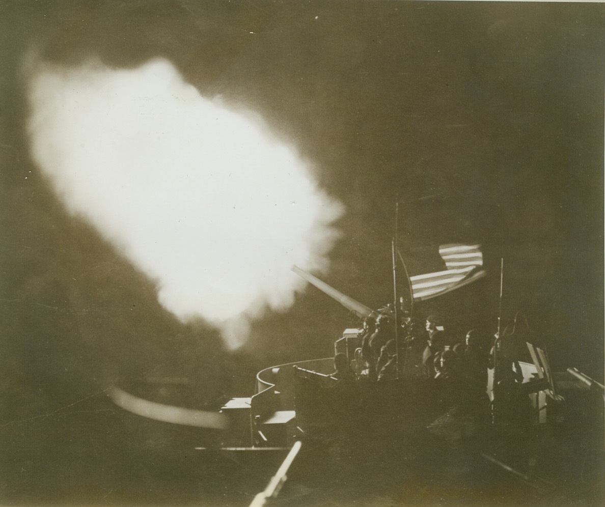 “Proof Thru the Night…”, 6/10/1943. Somewhere in the North Atlantic – Sending a fiery blast into North Atlantic skies from the deck of an American Destroyer, this gun casts a glow on “Old Glory” giving “proof thru the night that our flag was still there”. The gun crew went into action while escorting a United Nations convoy through sub-infested seas. Credit: (Official U.S. Navy Photo from ACME);