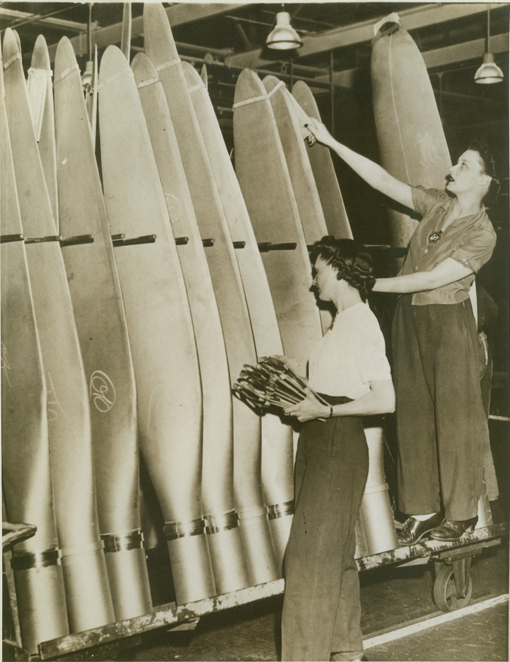 HOLLOW STEEL READY FOR THE SKYWAYS, 6/20/1943. PITTSBURGH DISTRICT, PA. – Gleaming hollow steel propellers, soon to whirr on United Nations warplanes, are checked on the final assembly line by Kathren Krumpe and Ann Newdonski, workers at a Curtiss-Wright propeller plant in the Pittsburgh district of Pennsylvania. The plant is reported to be the largest producer of hollow ground steel blades in the nation. Credit: ACME;