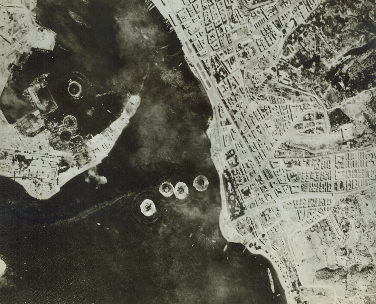 Softening Up Messina, 6/18/1943. Allied bombs are shown exploding on the strategic waterfront area of Messina Harbor in this photo taken from an American high altitude bomber. Without let-up, the daylight bombing of important cities such as this one along the southern coast of Italy continues. Credit (U.S. ARMY AIR FORCE PHOTO FROM ACME);