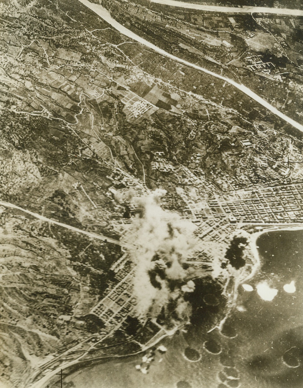 Reggio Gets Some of Pantelleria’s Medicine, 6/12/1943. REGGIO, ITALY – Now that Pantelleria has succumbed to the relentless Allied “invasion by air”, the United Nations air forces are turning full force on Mussolini’s mainland. Smoke and debris soar skyward as Reggio, a key Italian port at the tip of the boot, facing Sicily, feels the impact of Allied bombs. Both Reggio and San Giovanni are learning of the deadly accuracy of American bombardiers as they batter at the not-so-soft underbelly of Europe. Credit Line (Official U.S. Army Photo from Acme);