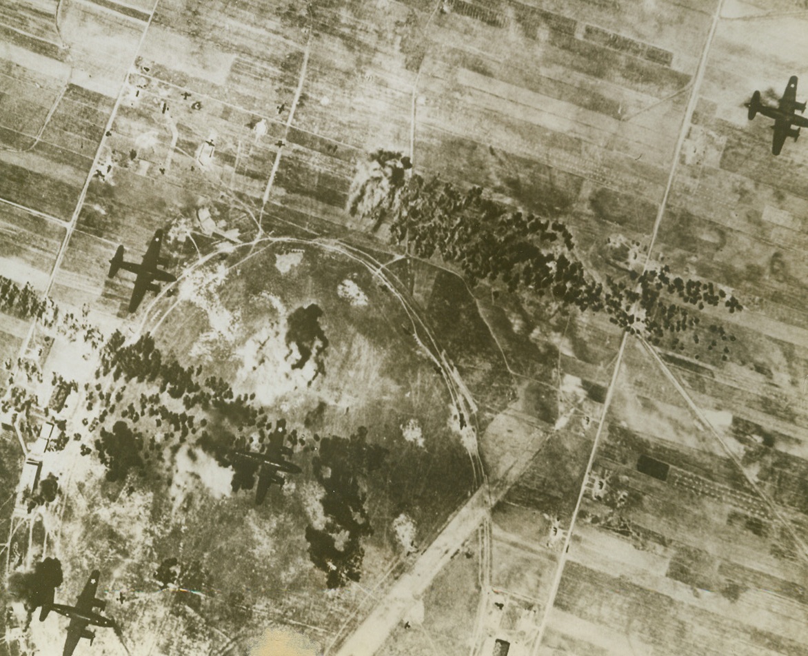 Characteristic View of Italian Airfield, 6/15/1943. American B-26 Marauders catch Italian planes flat-footed on the ground as they drop their sticks of bombs in the death-like pattern that has been ripping up Italian airfields. The plane in the upper right hand corner has just completed its job.  Credit Line (U.S. Army Air Corps Photo from Acme);