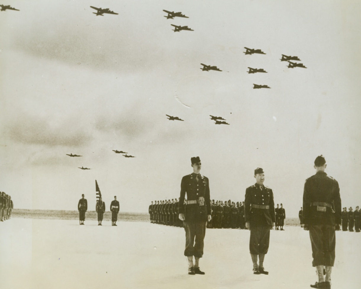 TWO YANK FIELDS IN ONE MONTH, 6/29/1943. SOMEWHERE IN ENGLAND—At ceremonies dedicating the second American-built and manned airfield completed in England during the last month, a detachment of U.S. Army Engineers stands at attention as Flying Fortresses of the U.S.A. 8th Air Force roar overhead. Brig. Gen. C.R. Woode, Harrisonburg, Va., Chief Engineer of the European Theater of Operations, turned the field over to Brig. Gen. Newton Longfellow, Minneapolis, Minn., commander of the Eighth Bomber Command, on June 17. Credit Line (ACME);
