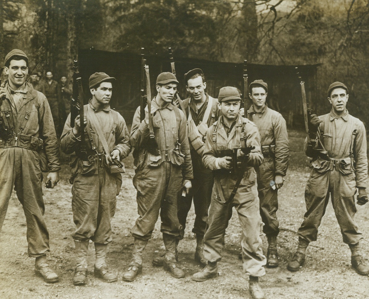 Ready For Invasion Day, 6/16/1943. Somewhere in England – Looking mighty tough, these U.S. Rangers perfect their skill with the “Tommy Gun” against the day when they’ll carry the deadly weapons into Europe and use them to mow Nazis down. Left to right: Pfc. John Toda of Sharon, PA; Pvt. John Dorzi of Barrington, R.I.; Pfc. Jack Homer of Dundalk, MD; Pfc. Robert Reese of McKeesport, PA; Lt. Eugene Dance of Beckley, W.VA; Cpl. Dale Ford, of Thurmont, MD; and Pfc. Manuel Viera of Cambridge, Mass. Credit: Official OWI Photo from ACME;