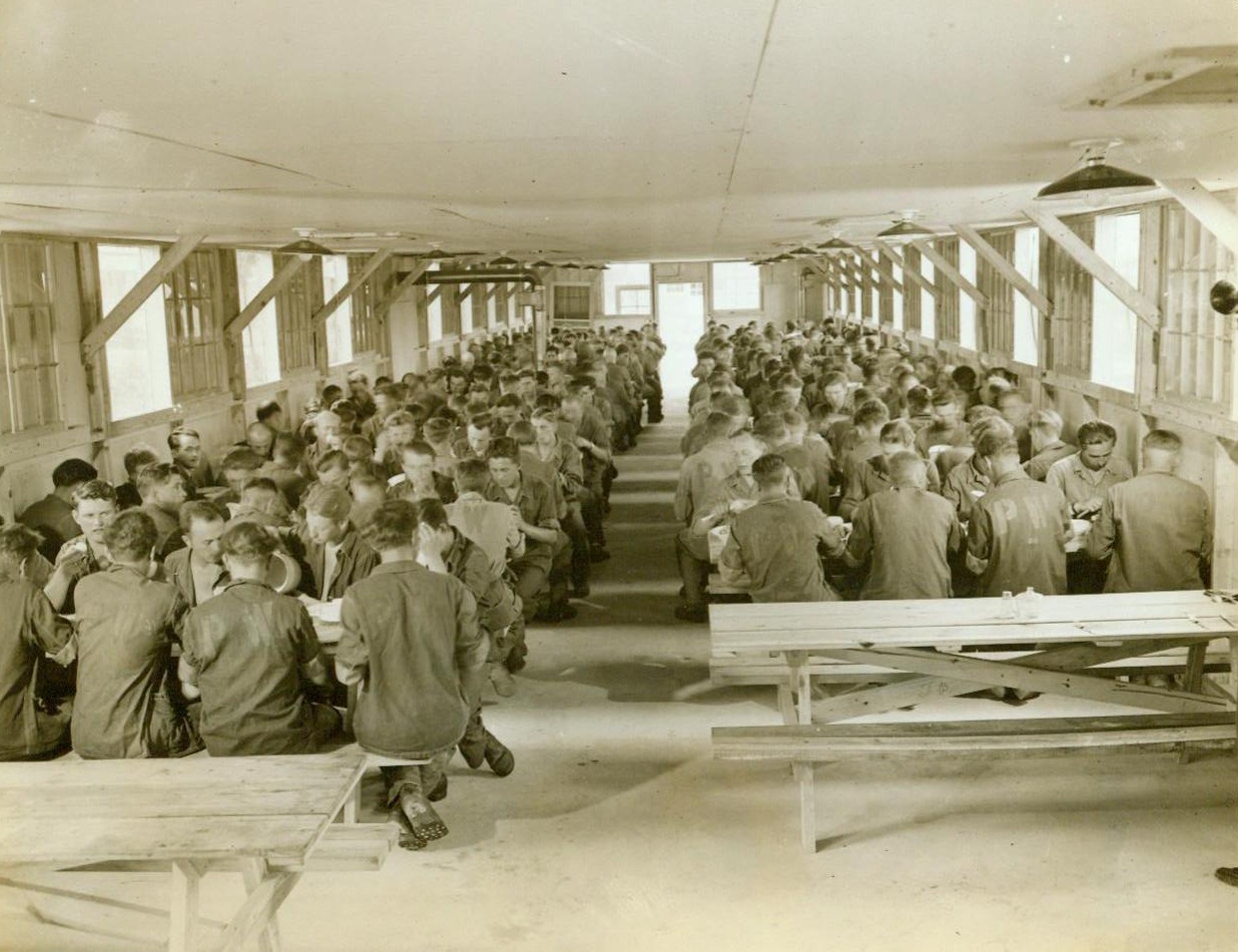 Chow Time At Prison Camp, 6/12/1943. Camp Breckinbridge, KY. - German prisoners of war are shown in the mess hall in the internment area at Camp Breckinbridge, KY., One of the country's many prison camps now being filled with German and Italian captives who are being interned separately. The average camp houses 2,000 prisoners and requires about 500 officers and enlisted men of the Army for proper guarding. The standard stockade at each of the prison camps is an enclosure within a double barbed wire fence, with guard towers covering the narrow alley between the fences. 6/12/43 (ACME);