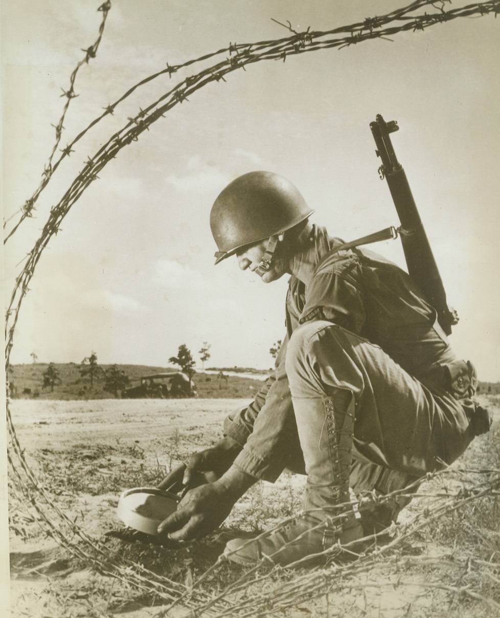 Touchy Business, 6/10/1943. Louisiana—The task of laying mines is almost as delicate as finding them on an enemy field. Here PFC Leonard A. Keller, of Mission, Tex., is learning how to handle the deadly “cakes” as he trains for his job on the fighting front during Third Army maneuvers in Lousiana.  Credit: ACME;