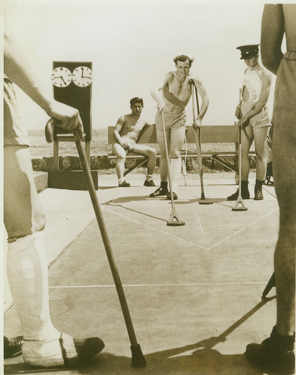 Crutches and Canes and Shuffleboard, 6/4/1943. San Diego, Calif.—Takes more than crutches and canes to sink the morale of Uncle Sam’s gobs. In spite of their injuries, these boys enjoy a game of shuffleboard during an outing for patients of the San Diego Naval Hospital. M.R. McConnell, shipfitter third class, leans on his crutch as he sends a disc down the deck. Credit: Official U.S. Navy photo from ACME.;