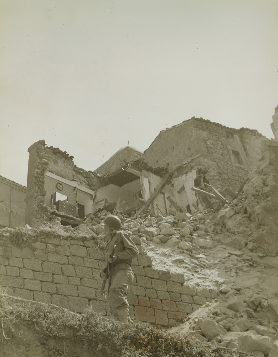 NO TIME FOR SENTIMENT, 8/14/1943. SICILY—To those given to contemplation, these jagged shells of the once peaceful homes of Troina, Sicily, present a sorry sight—mute evidence to the terrible destruction of this war which the Axis wished on itself—but to Pvt. William Saleski, Wilkes Barre, Pa., they are mighty good hiding places. He holds his gun ready as he watches for enemy snipers. Credit: Acme;